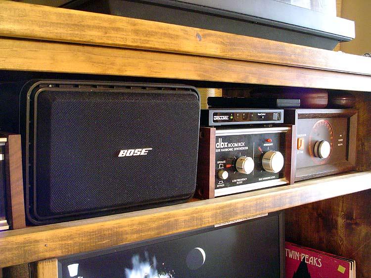 boombox.jpg - Center stage, a true video monitor speaker that gives a brilliant edge to vocals when driven with the L+R output of the Carver H9AV. Double shielded, so no interference from all the other electronics. Next to that is a dbx BoomBox sub-sonic synthesizer that takes the lowest octave of the source material - and adds one more below it for earth shattering bass. Last but not least, a Magnum FM Sleuth antenna amplifier that can take a barely readable signal and make it sound like it's next door.
